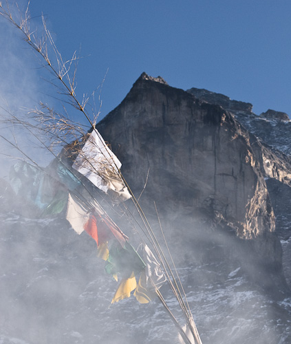 Prayer flags and smoke from burning juniper in Khunde